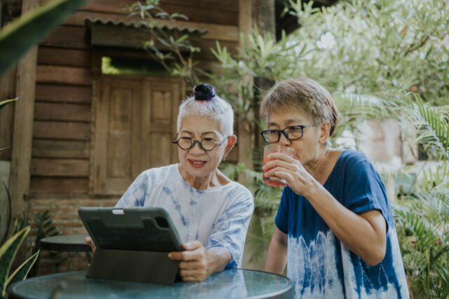 Two people sitting outside and looking at a tablet together