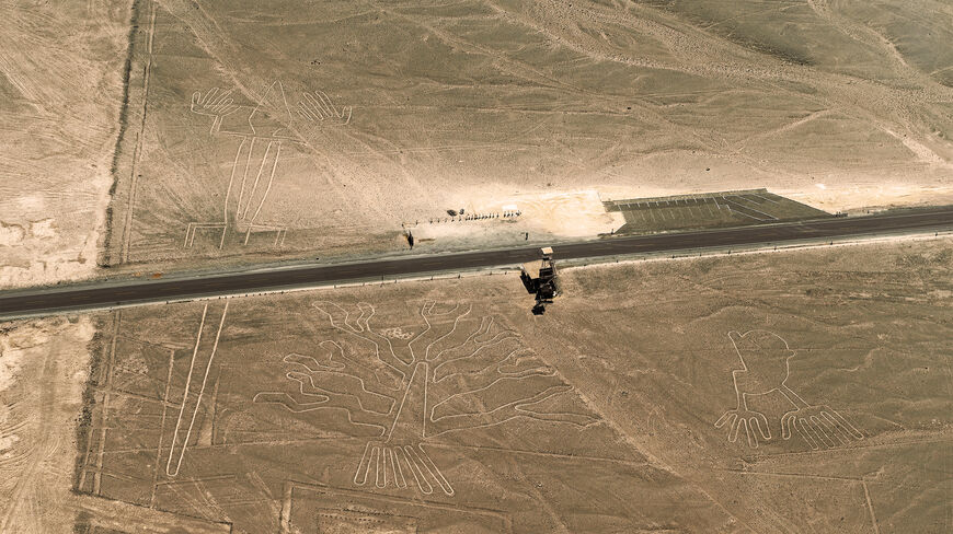 Aerial view of Nazca Lines in Peru showing geoglyphs of a tree and hands near a road in a desert landscape.